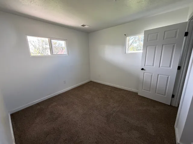 Unfurnished room featuring dark colored carpet and a textured ceiling