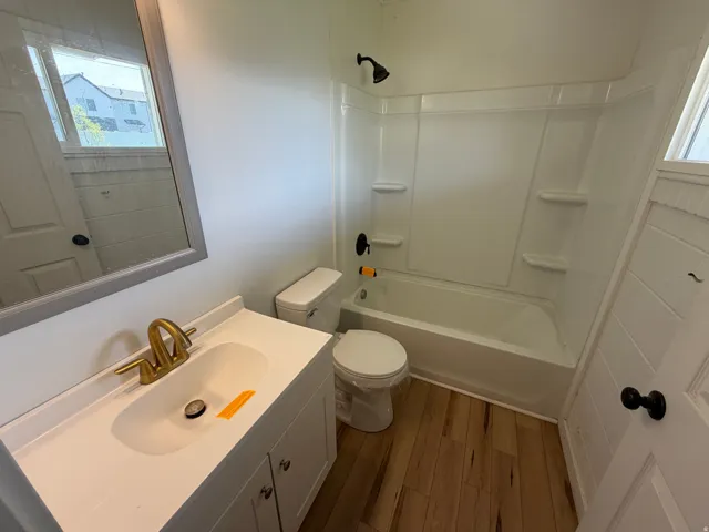 Bathroom with vanity, wood finished floors, and shower / washtub combination