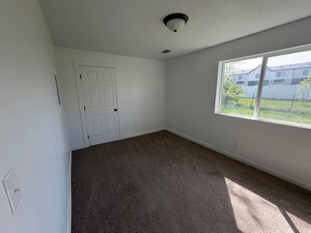 Empty room with dark colored carpet and a textured ceiling