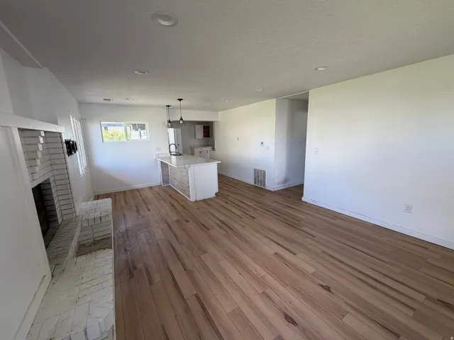 Unfurnished living room featuring a fireplace, light wood-type flooring, recessed lighting, and a textured ceiling