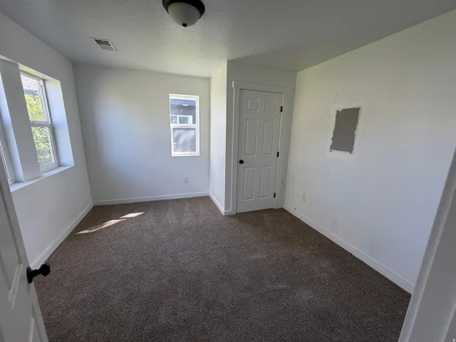 Unfurnished room with dark colored carpet, a textured ceiling, and healthy amount of natural light