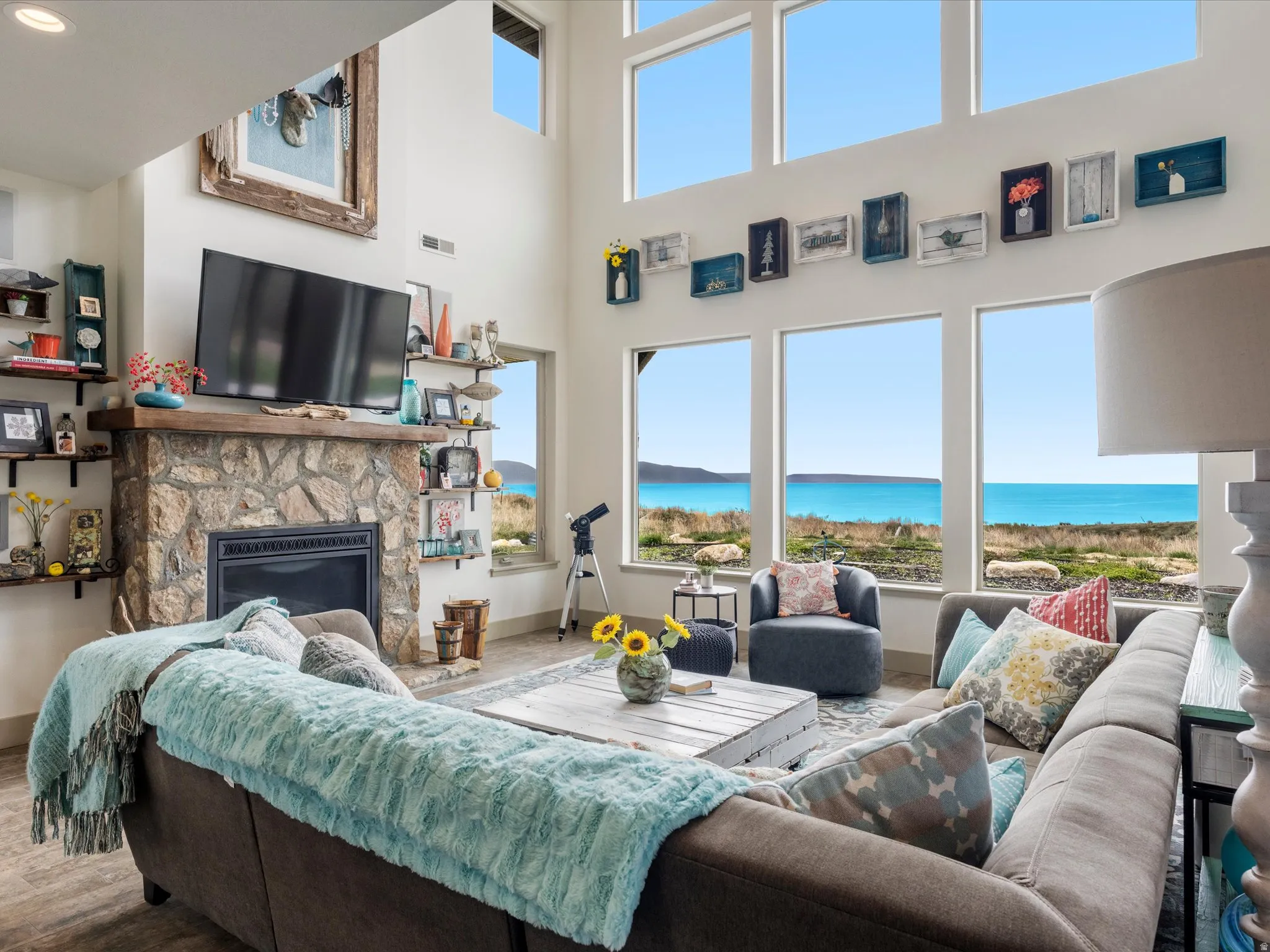 Living room featuring a stone fireplace, wood finished floors, plenty of natural light, with an amazing lake view and full height vaulted ceiling