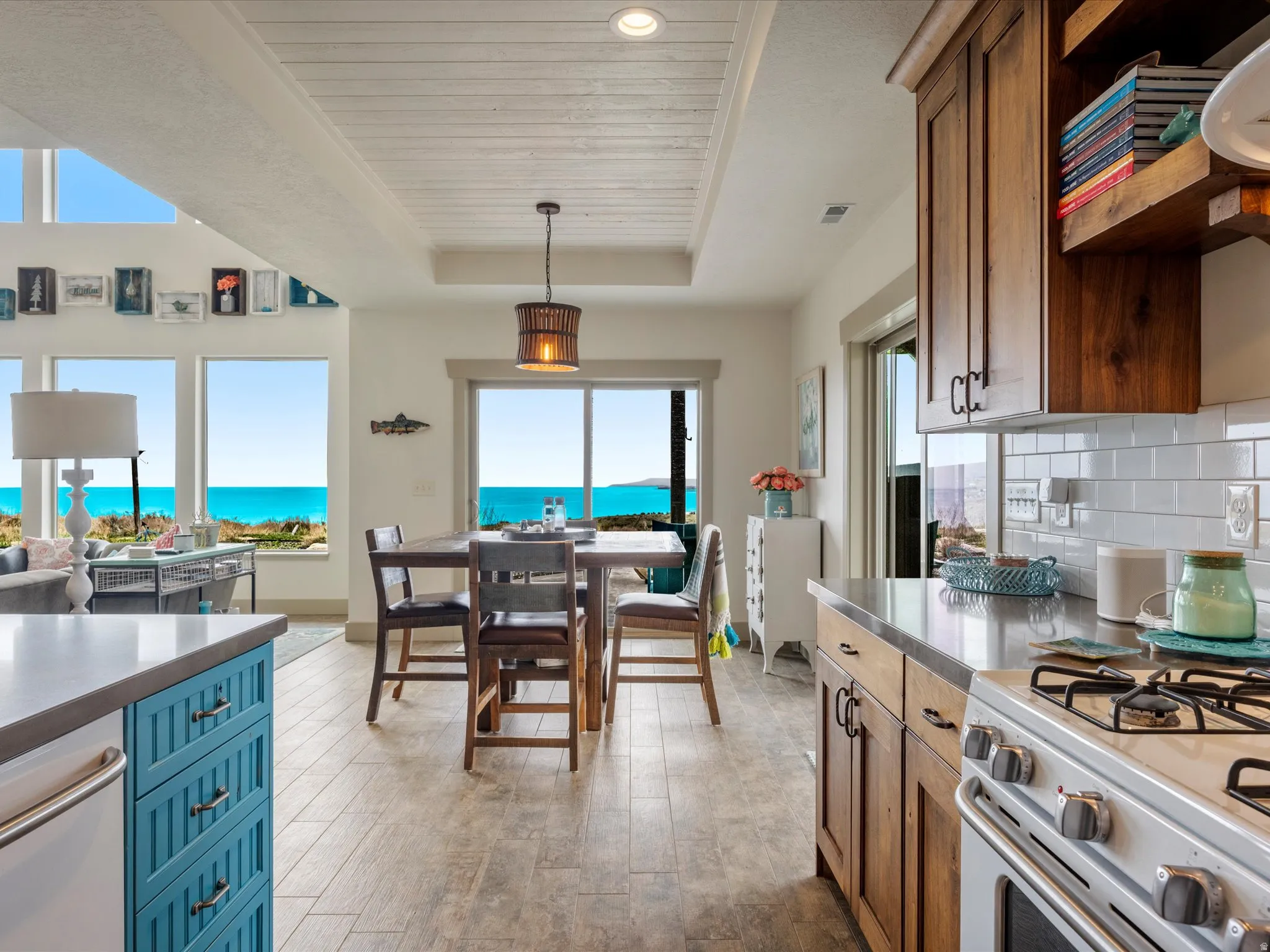 Kitchen featuring white gas range oven, a wooden tray ceiling, light wood-type flooring, tasteful backsplash, and a lake view