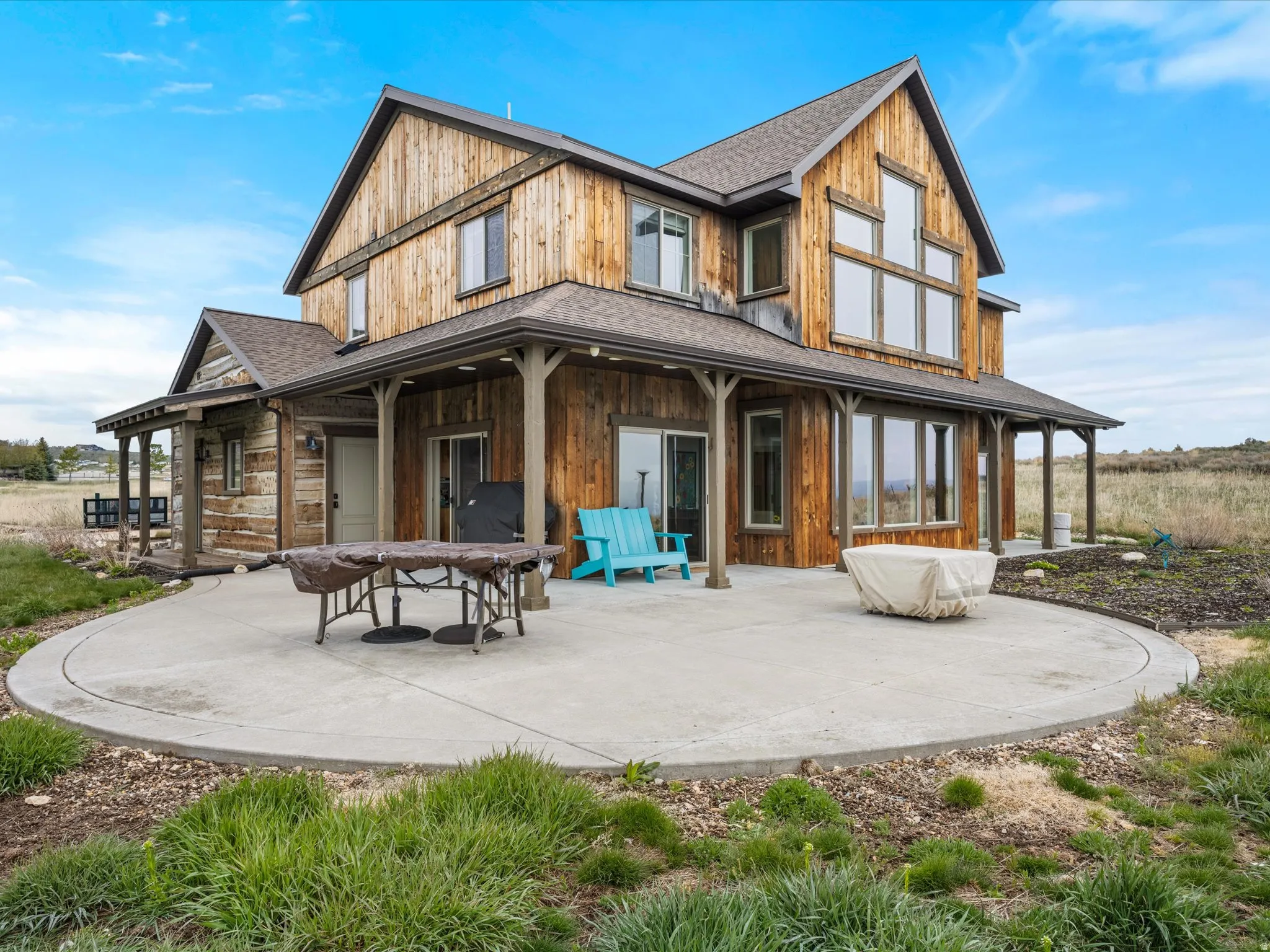 Back of house with a shingled roof and a large porch with firepit