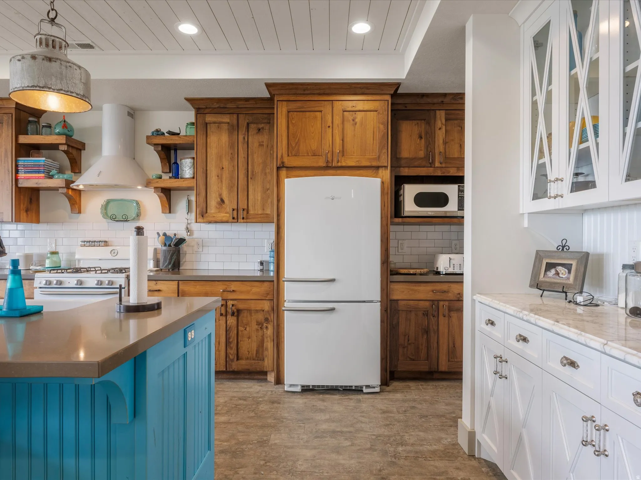 Two tone kitchen featuring two tone cabinets, white appliances, extractor fan, glass insert cabinets, and open shelves