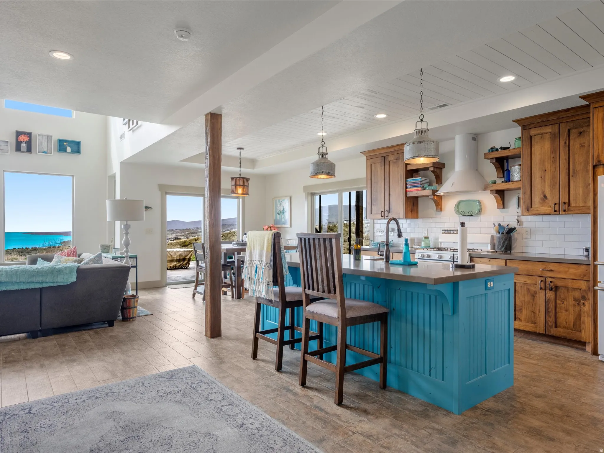Dual tone kitchen with a breakfast bar, a kitchen island with sink, two tone cabinets, light wood finished floors, and decorative backsplash