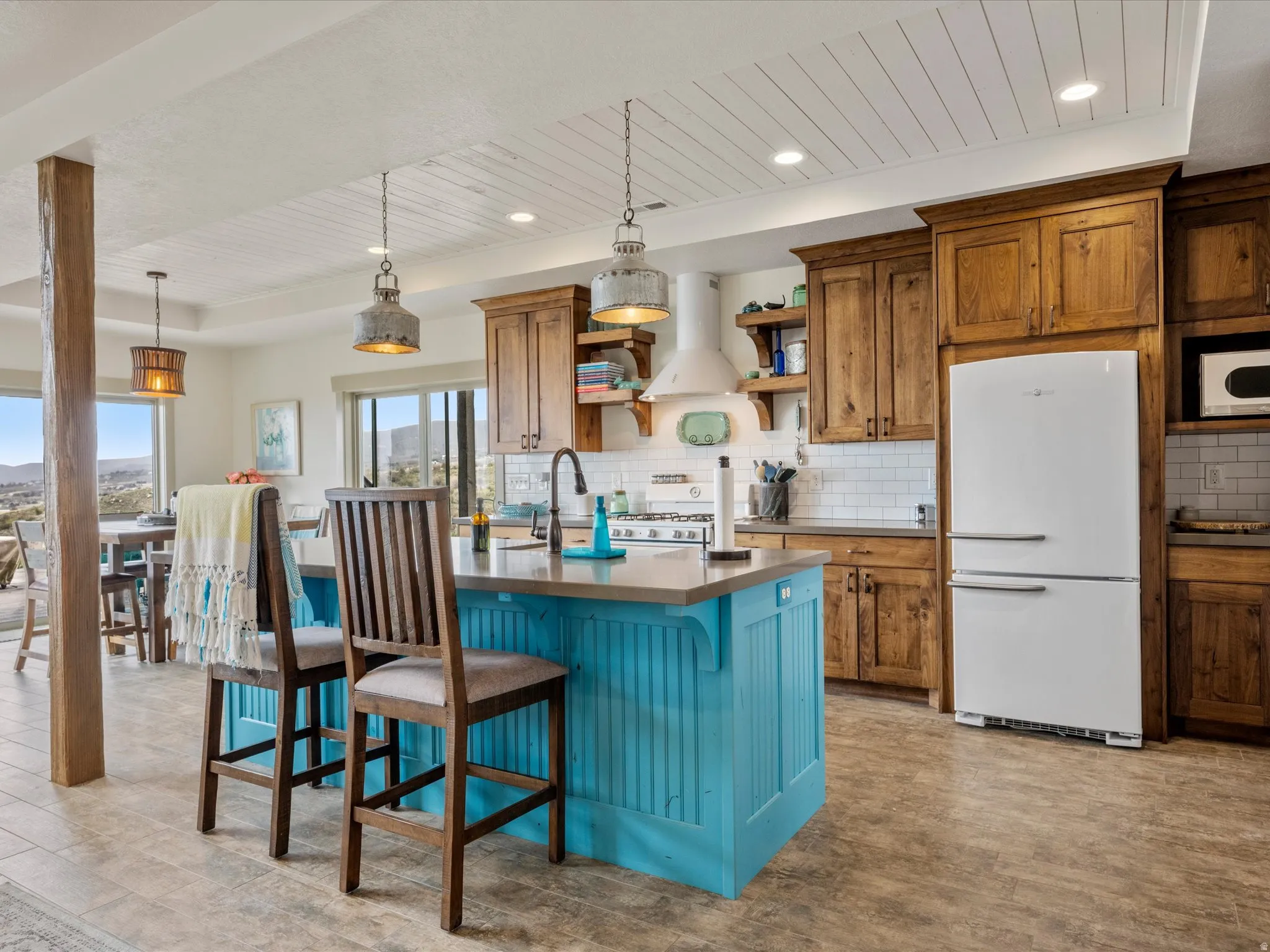 Kitchen with white appliances, a breakfast bar area, open shelves, dual tone cabinetry, and backsplash
