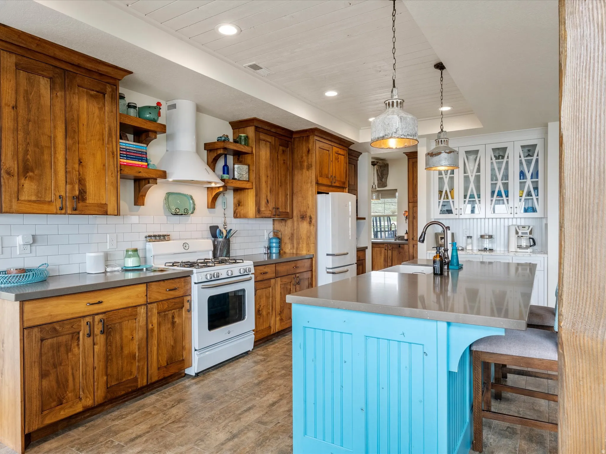 Kitchen with white appliances, light wood-style floors, a large island, a wooden tray ceiling, and a breakfast bar