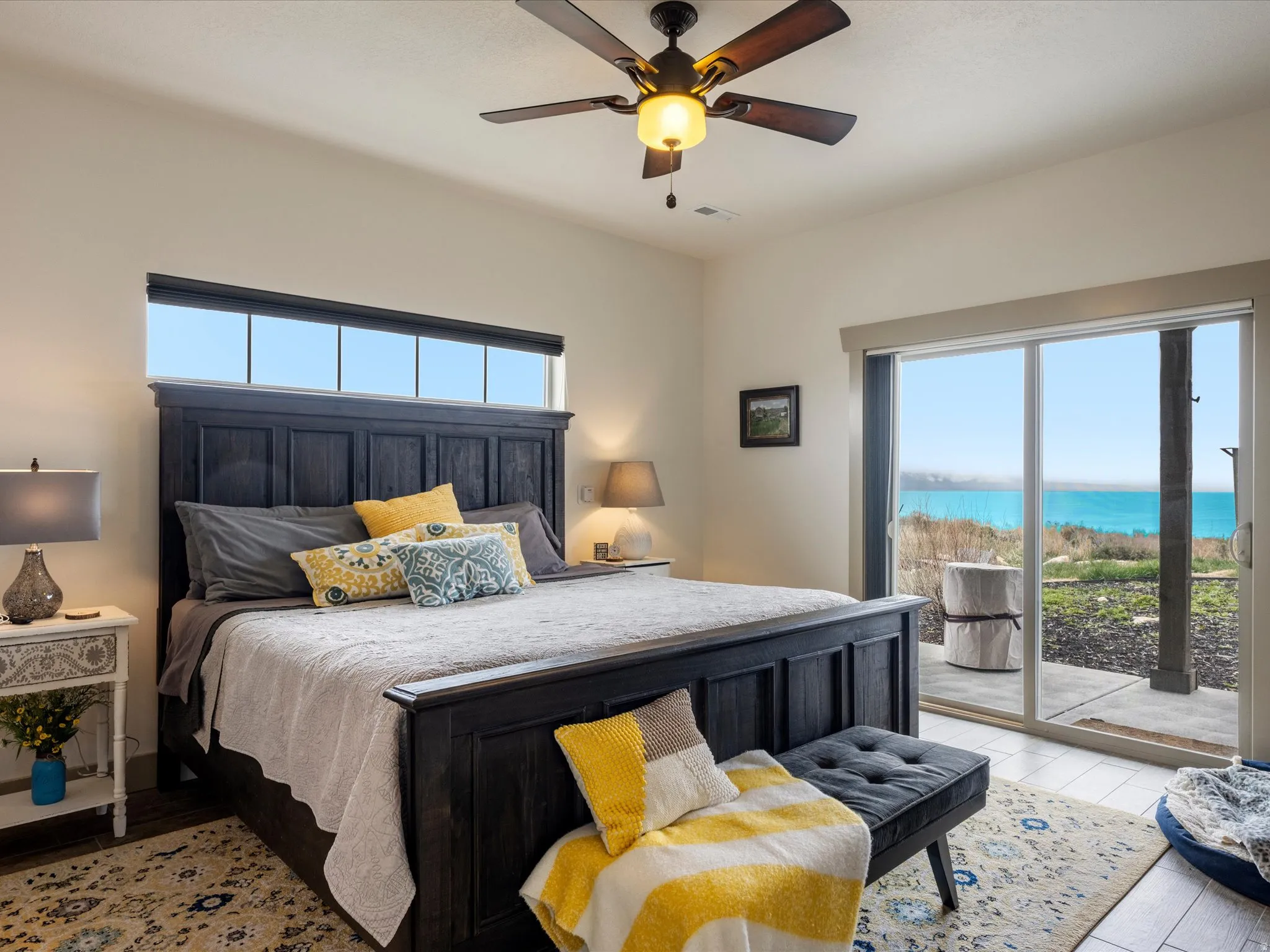 Primary Bedroom featuring a water view, with a fireplace, ceiling fan, access to outside, and light wood-style floors