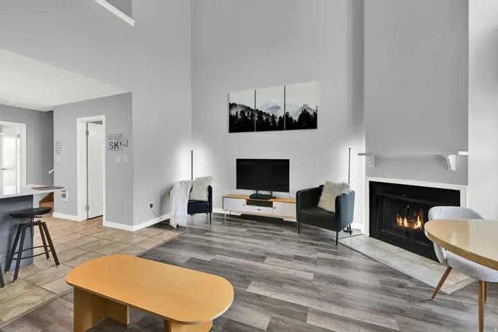 Lofted living room with upgraded, neutral LVP flooring, wood burning fireplace and modern finishes.