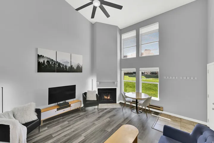 Lofted living room with upgraded, neutral LVP flooring, wood burning fireplace and modern finishes. New windows let in natural light.