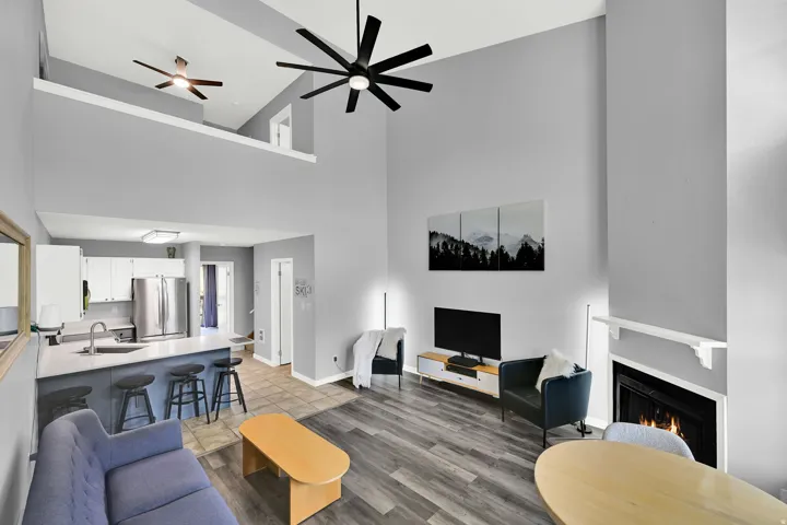 Lofted living room with upgraded, neutral LVP flooring, wood burning fireplace and modern finishes.