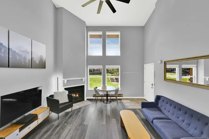 Lofted living room with upgraded, neutral LVP flooring, wood burning fireplace and modern finishes. New windows let in natural light.