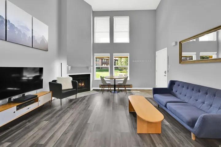 Lofted living room with upgraded, neutral LVP flooring, wood burning fireplace and modern finishes. New windows let in natural light.
