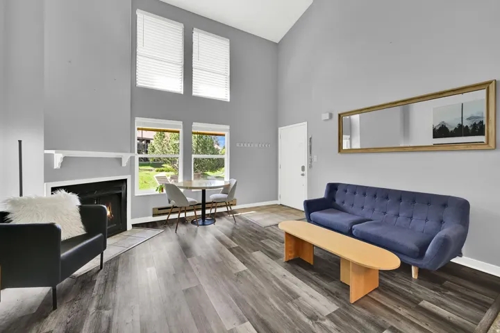 Lofted living room with upgraded, neutral LVP flooring, wood burning fireplace and modern finishes. New windows let in natural light.