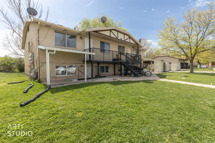 Front of property featuring brick, a yard, and a balcony