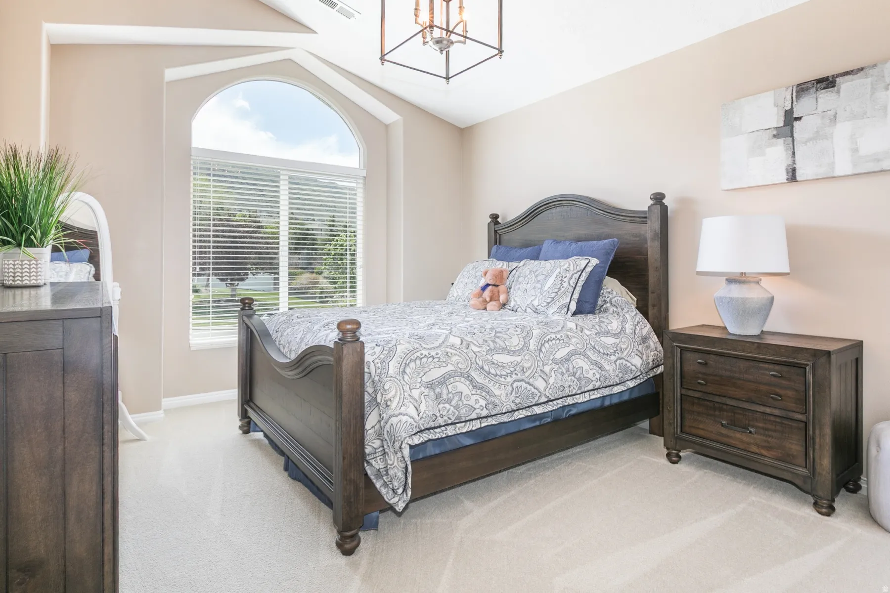 Bedroom with hanging light, light carpet, and vaulted ceiling