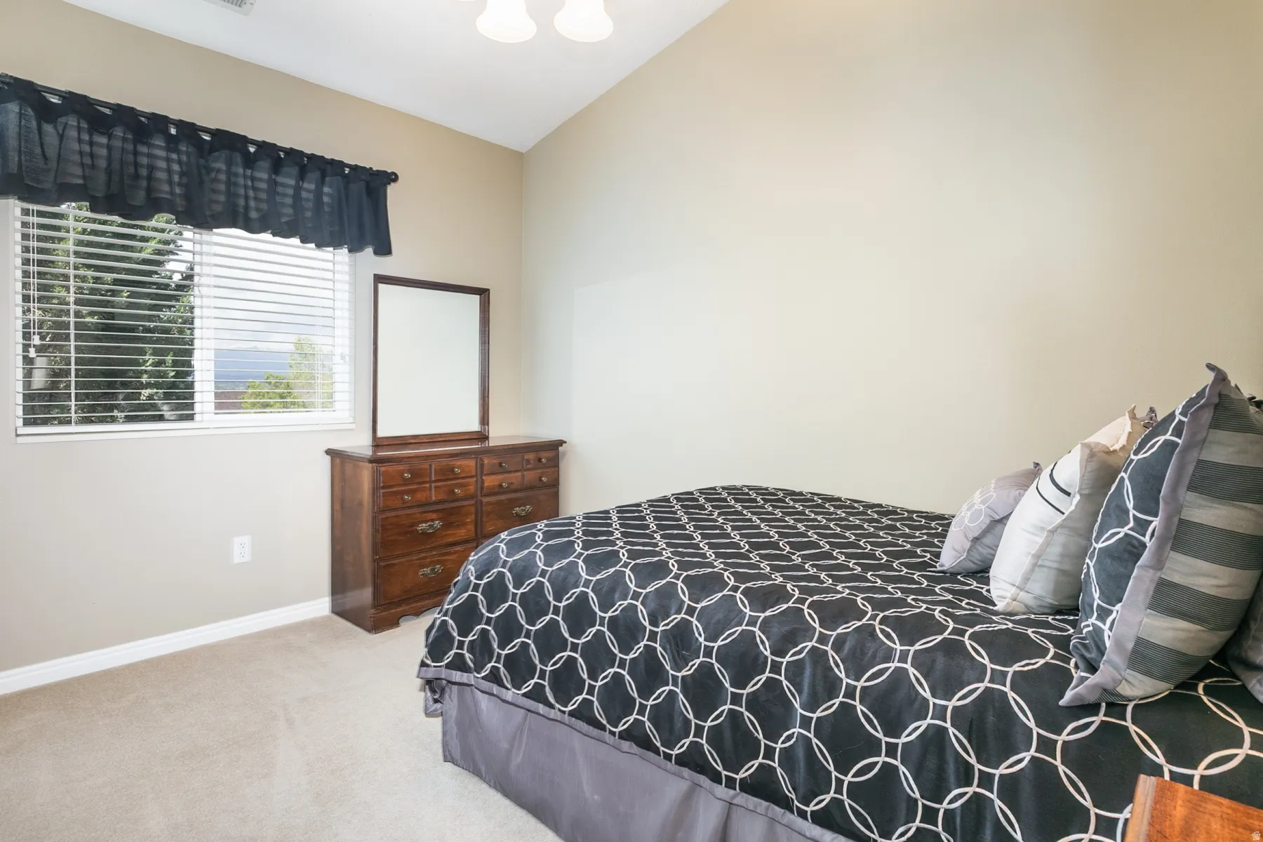Bedroom with light carpet, lofted ceiling,
