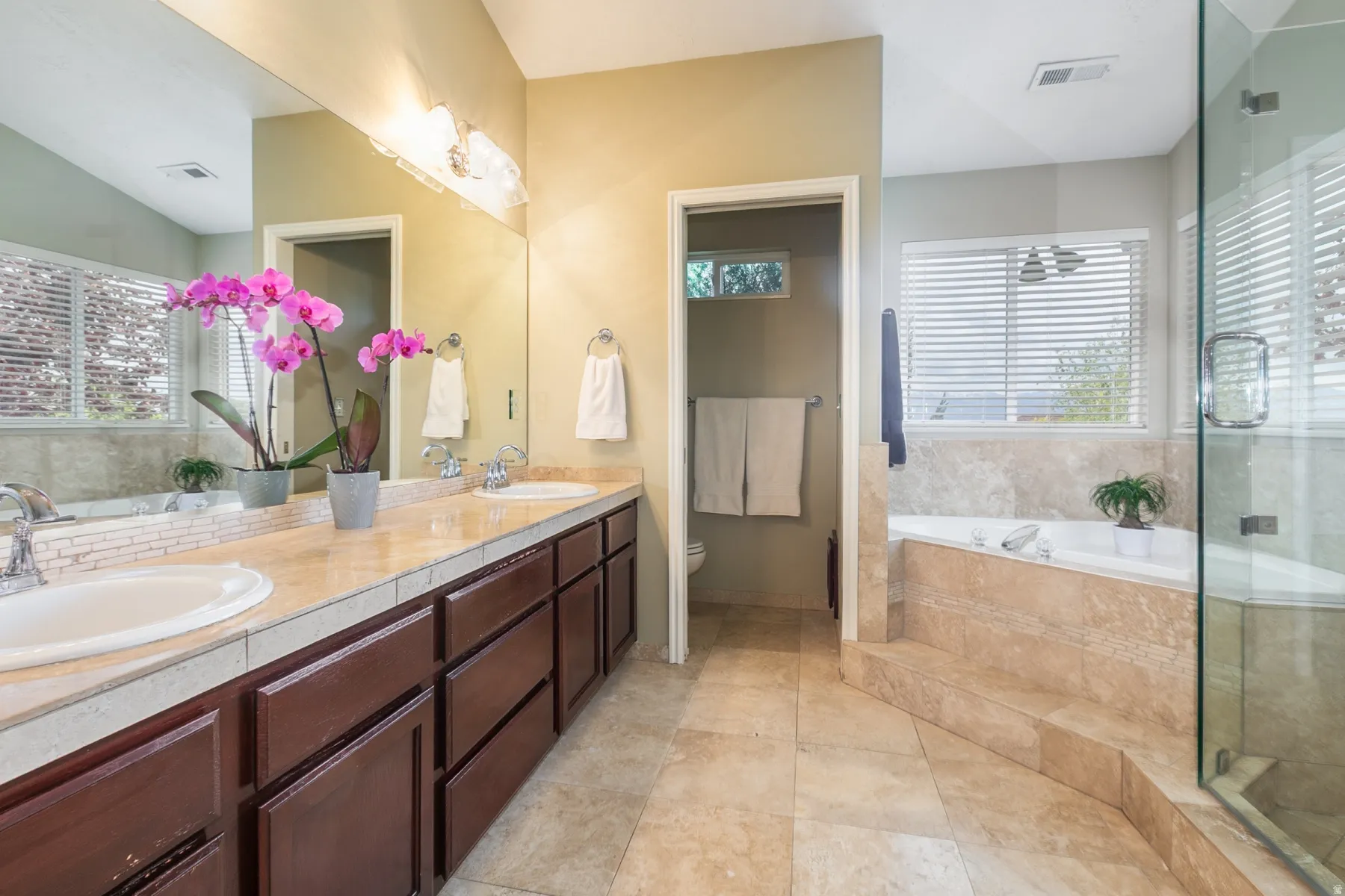Primary ensuite full bath with a garden tub, double vanity, and a stall shower