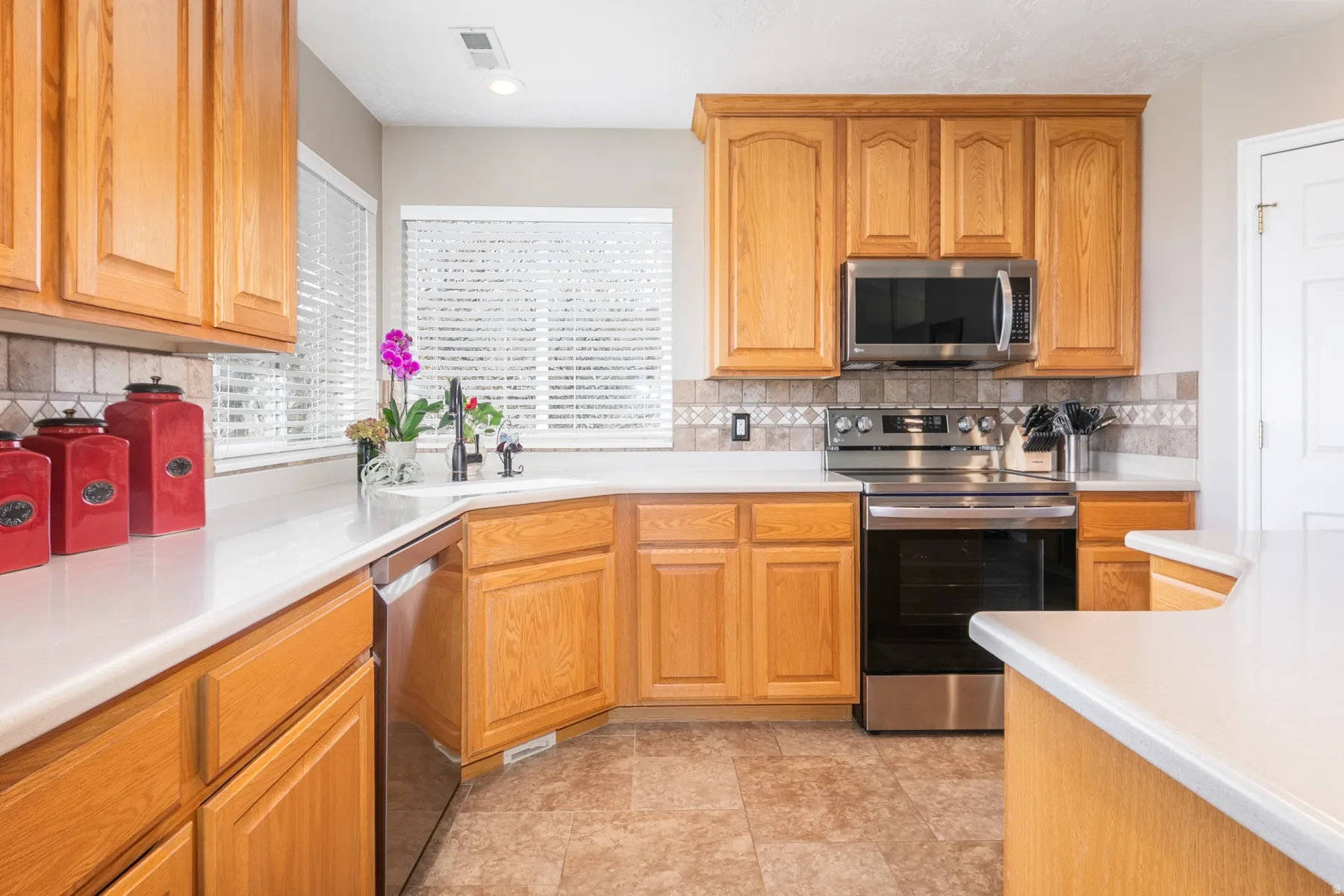 Kitchen with stainless steel appliances, light countertops, wood finish cabinetry, and decorative backsplash