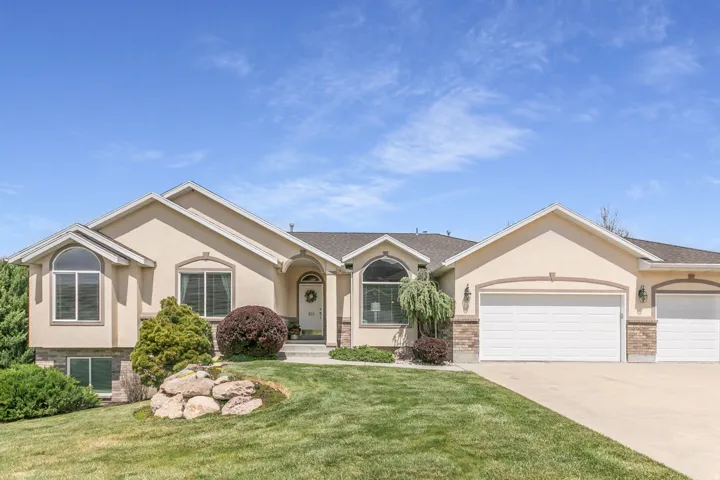 Ranch-style house featuring stucco siding, an attached garage, driveway, and a front lawn