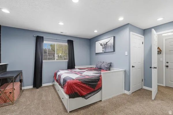 Bedroom featuring light carpet, recessed lighting, and a textured ceiling