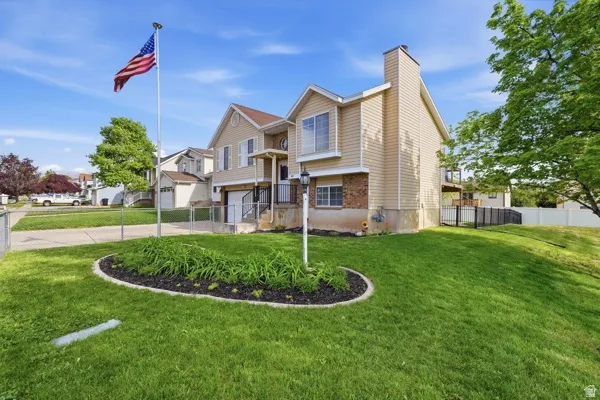 Raised ranch with driveway, an attached garage, a chimney, and brick siding
