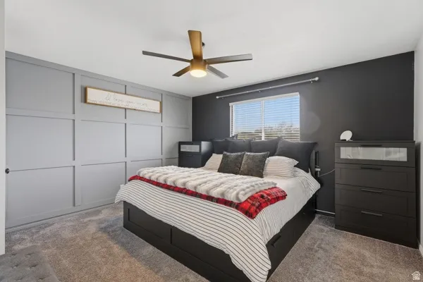 Bedroom with carpet floors, a ceiling fan, and a decorative wall