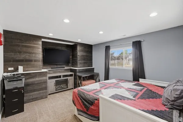 Bedroom featuring wood walls, light carpet, recessed lighting, and an accent wall