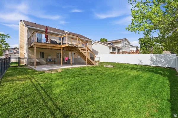 Rear view of house with a fenced backyard, a patio, and a wooden deck