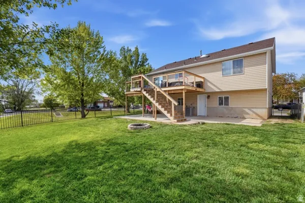 Back of house featuring a fenced backyard, a patio area, a wooden deck, and a fire pit