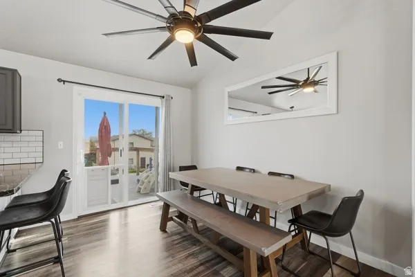 Dining space with a ceiling fan, dark wood finished floors, and vaulted ceiling