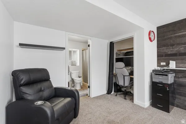 Living area with an office area, light colored carpet, and wood walls