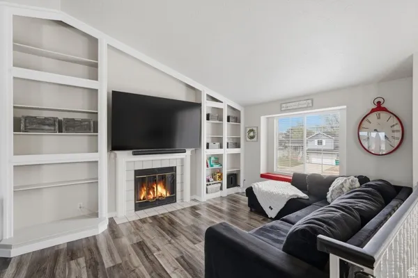 Living room featuring a fireplace, dark wood-style flooring, and built in features