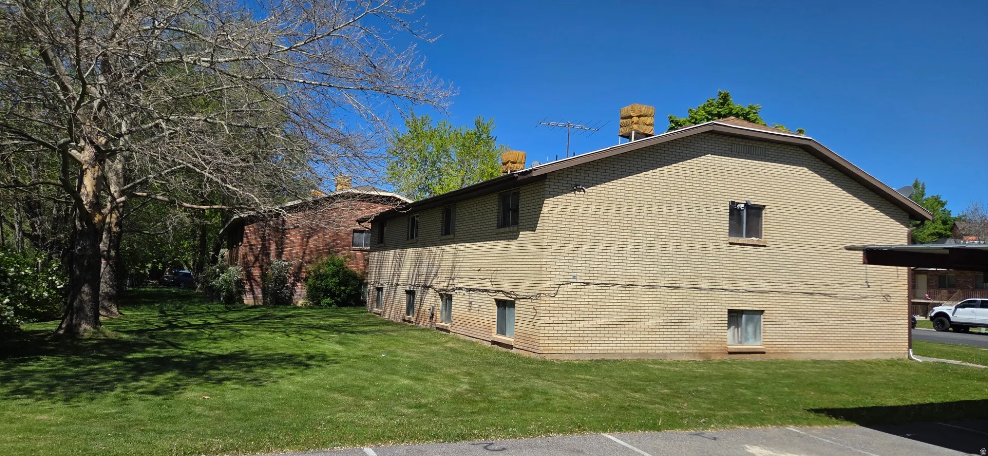 View of property exterior with a yard, uncovered parking, and brick siding