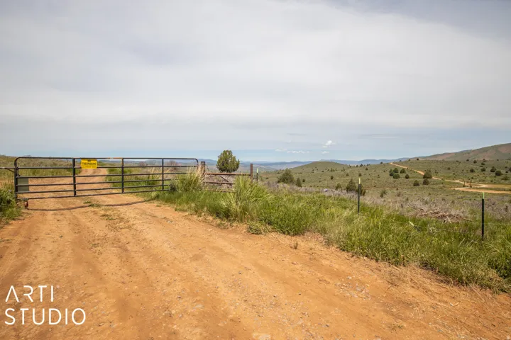 View of street with a rural view, a gated entry, a gate, and a mountain view