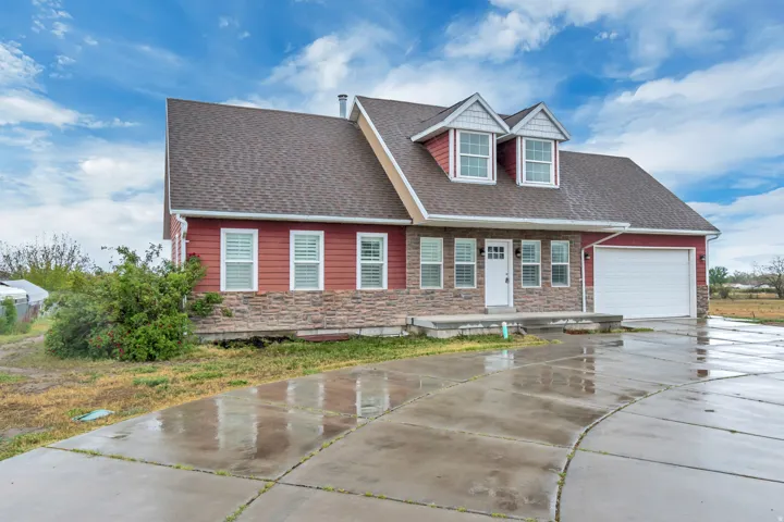 View of front of house featuring stone siding, roof with shingles, concrete driveway, and a garage