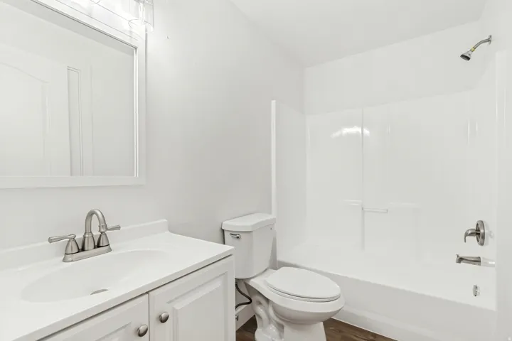 Full bathroom featuring vanity, washtub / shower combination, and dark wood-type flooring