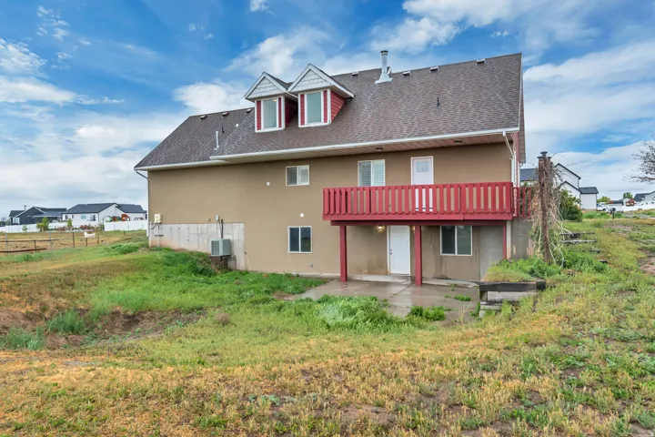 Rear view of property featuring a patio, roof with shingles, stucco siding, and a balcony