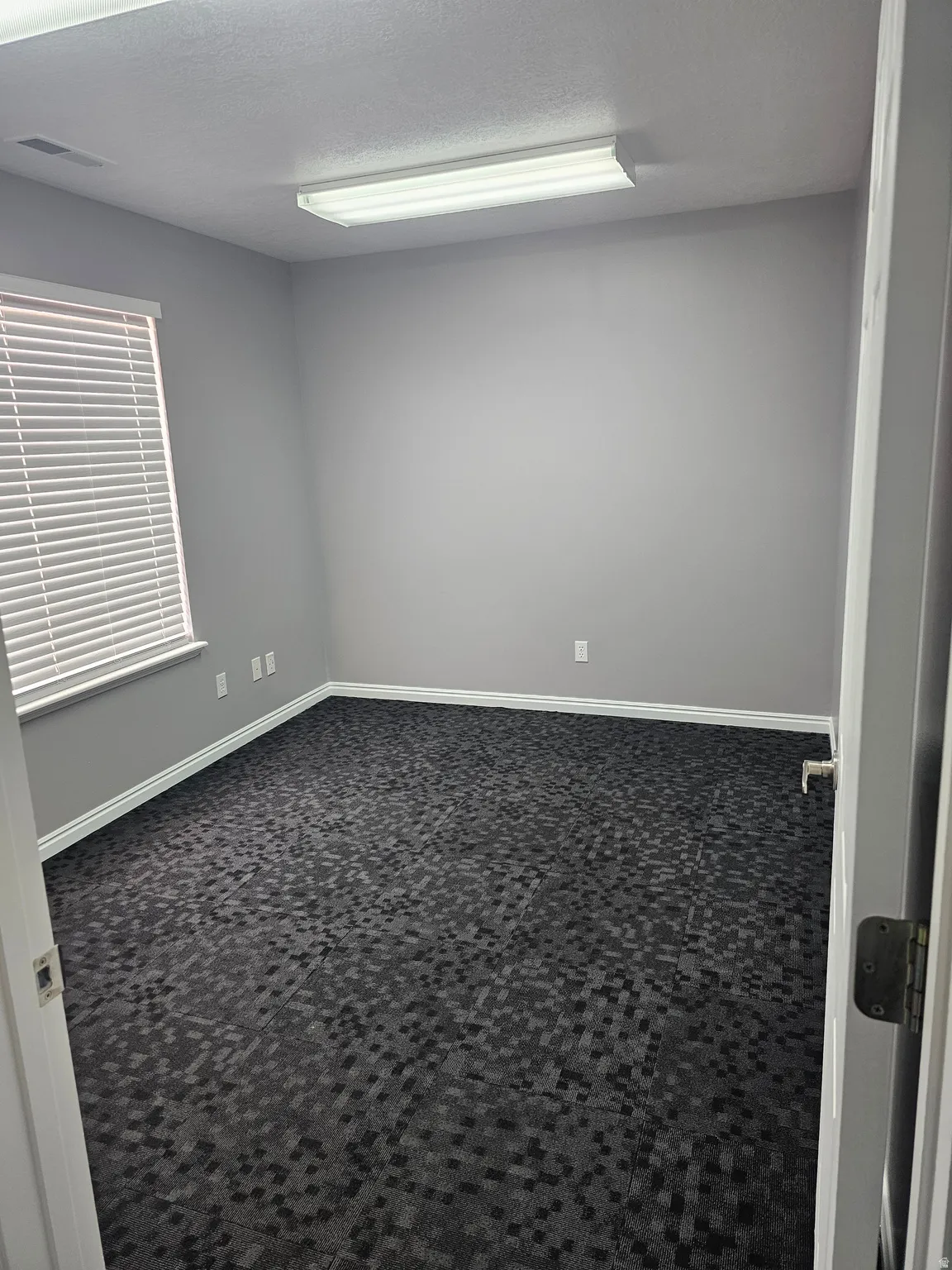 Unfurnished room with dark carpet and a textured ceiling