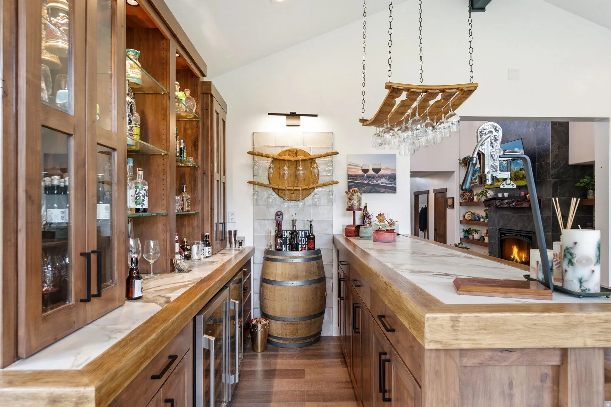 Indoor bar with wooden counters, open shelves, lofted ceiling, a warm lit fireplace, and wood finish cabinets