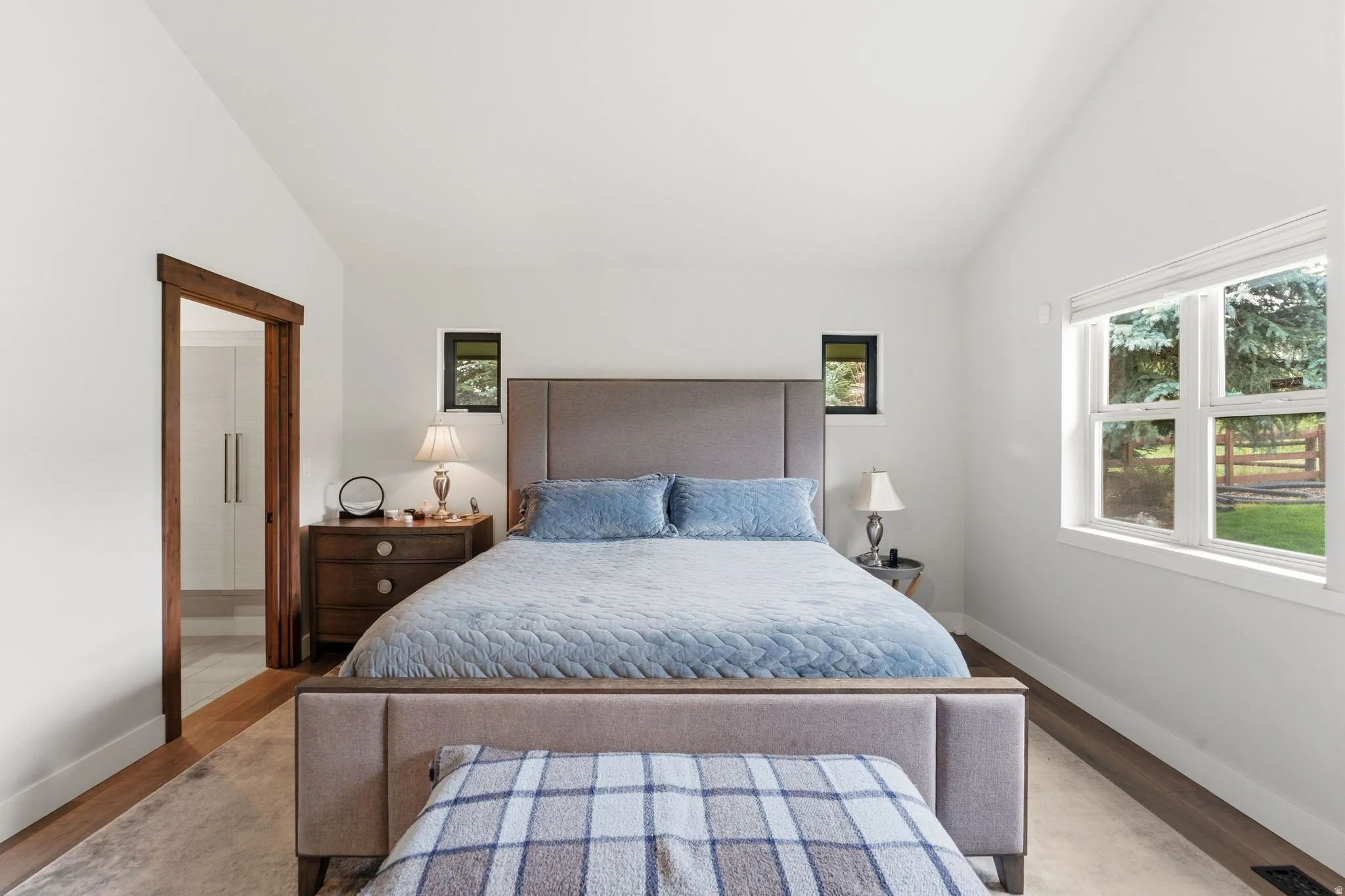 Bedroom featuring lofted ceiling, wood finished floors, and ensuite bathroom
