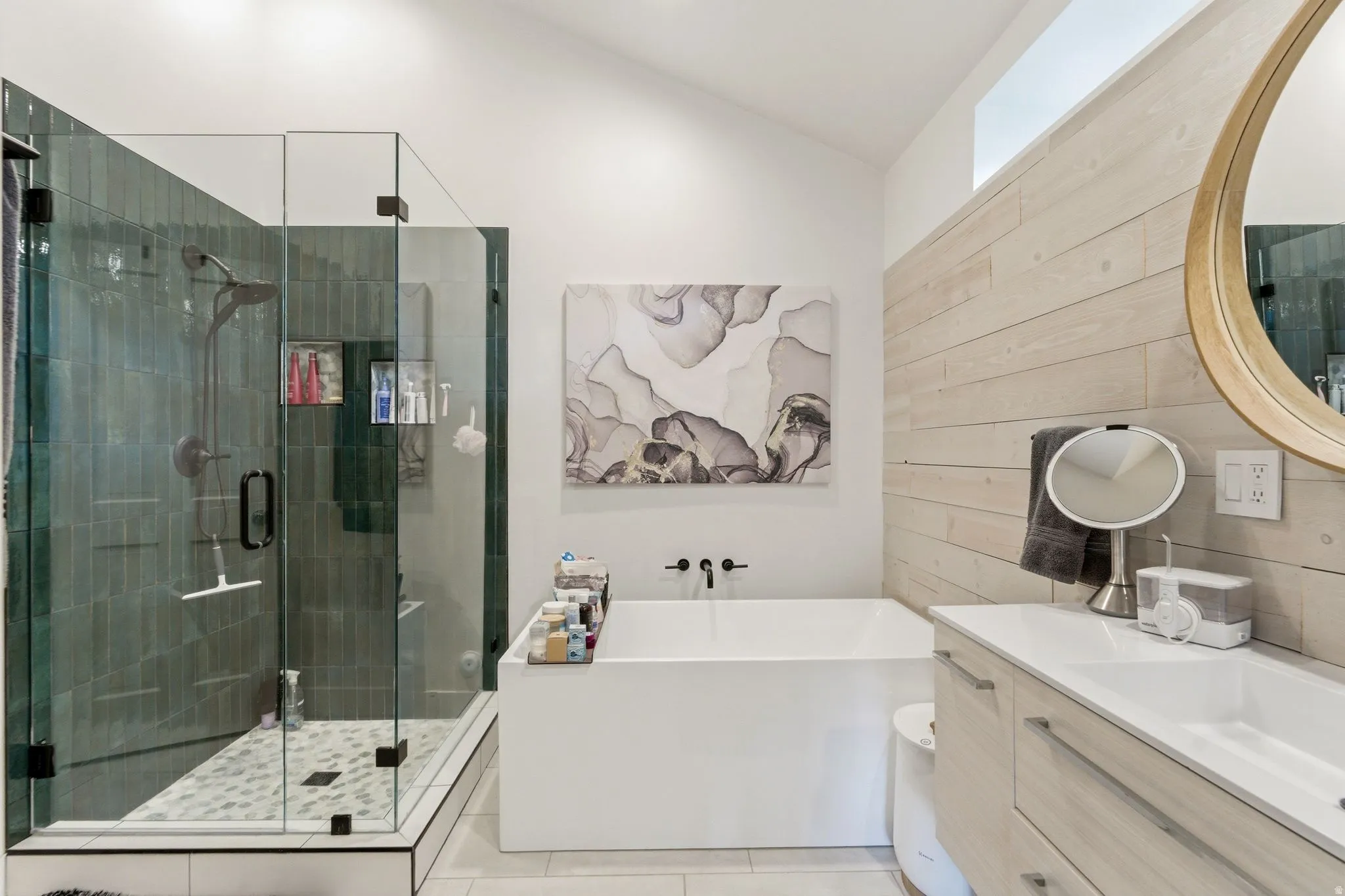 Bathroom featuring vanity, lofted ceiling, a soaking tub, a stall shower, and light tile patterned floors