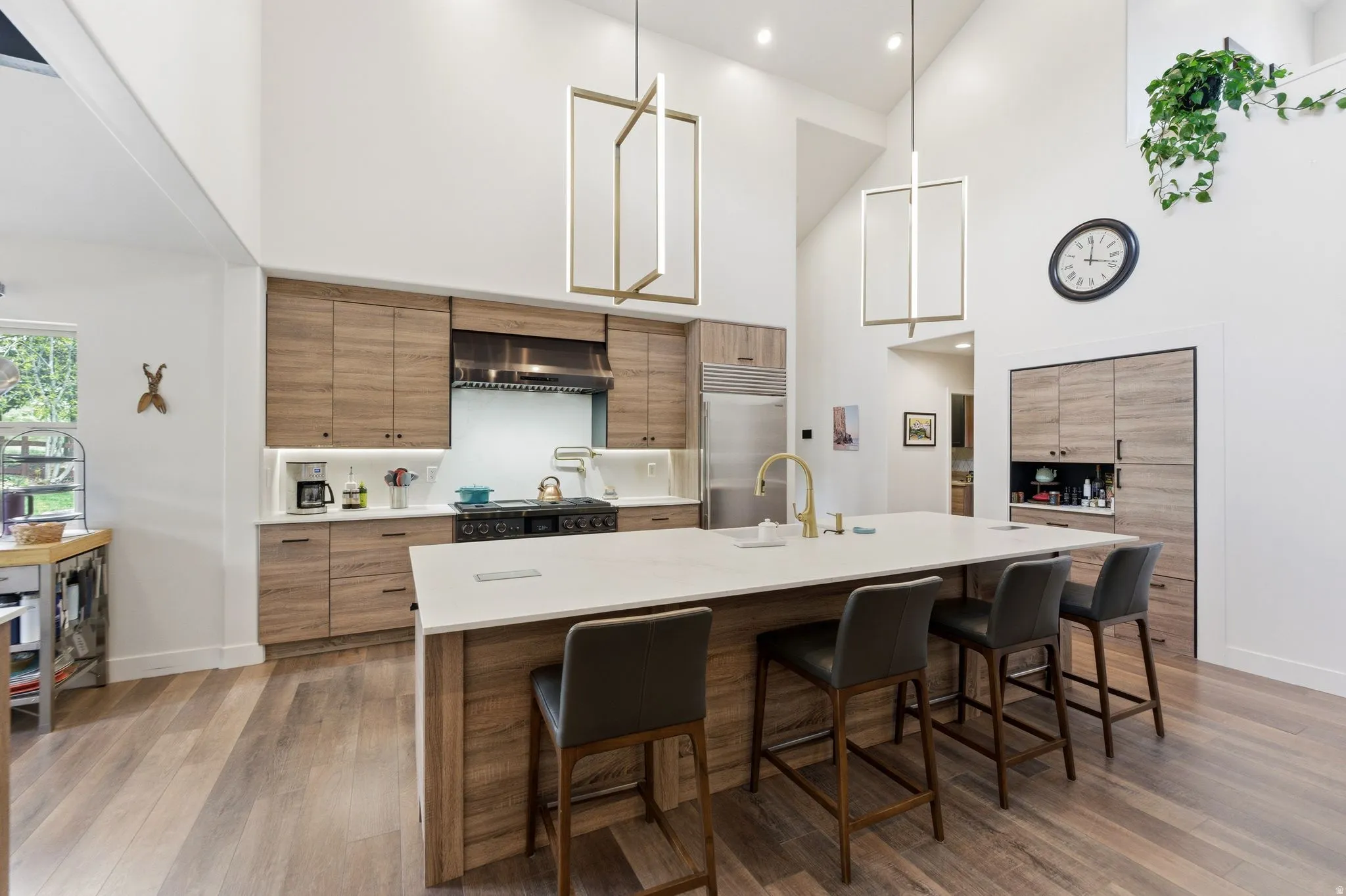 Kitchen with modern cabinets, a breakfast bar, stainless steel built in refrigerator, a high ceiling, and a large island with sink