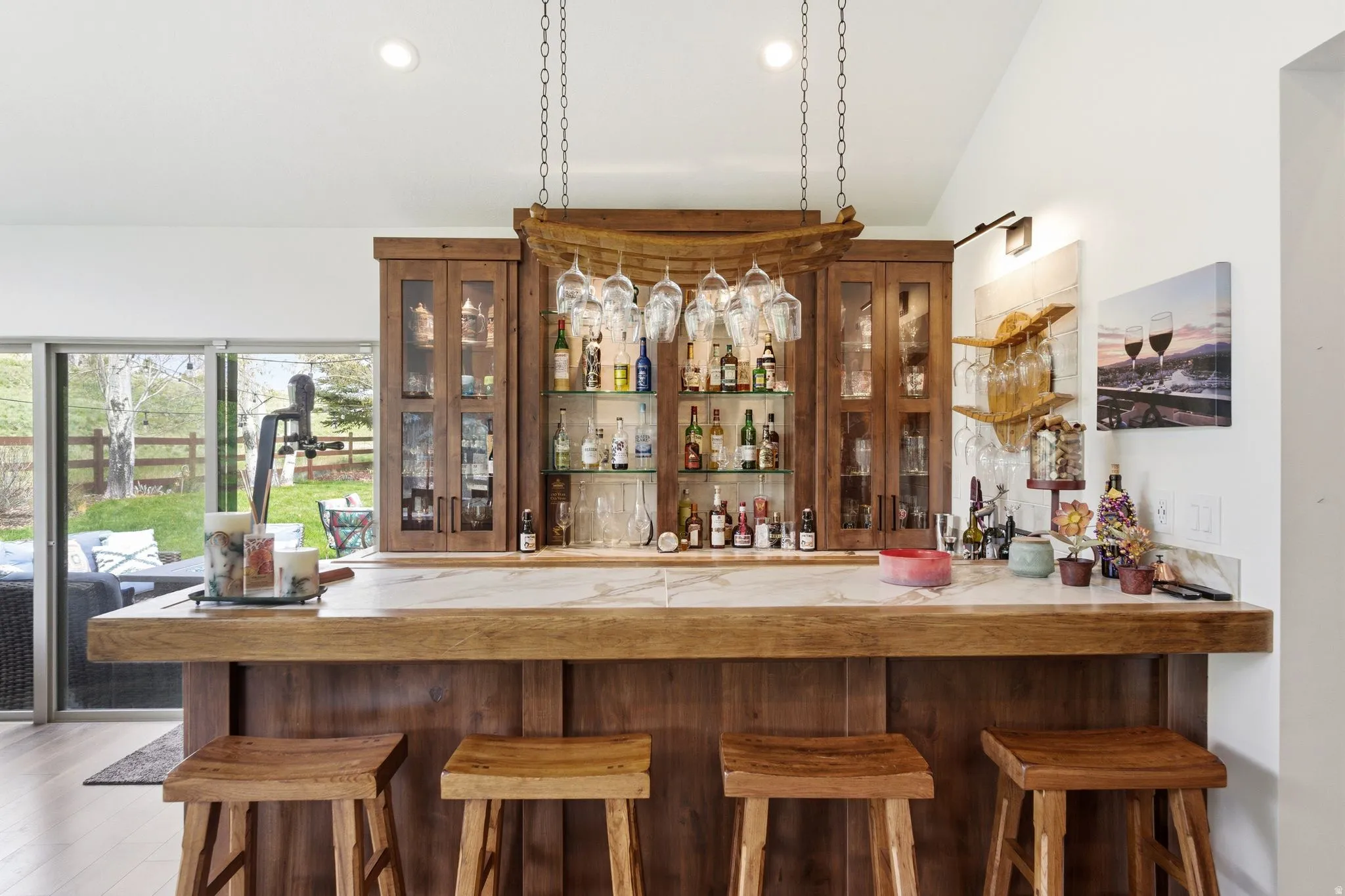 Indoor bar with light countertops, glass fronted cabinets, recessed lighting, vaulted ceiling, and light wood-type flooring