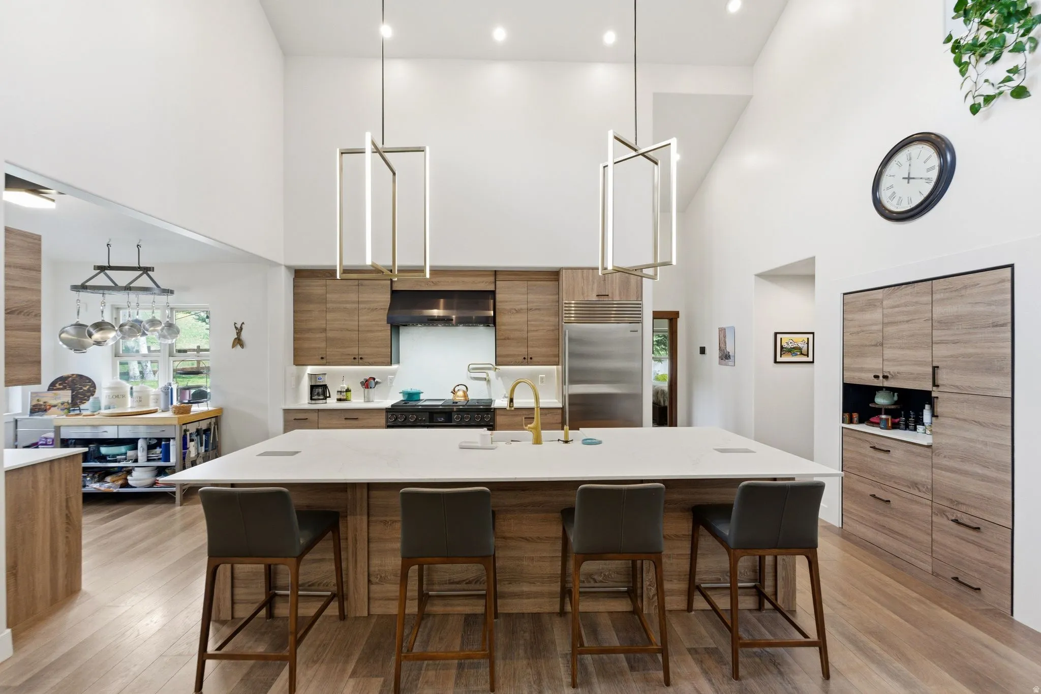 Kitchen with modern cabinets, a breakfast bar, a large island, light stone counters, and decorative light fixtures