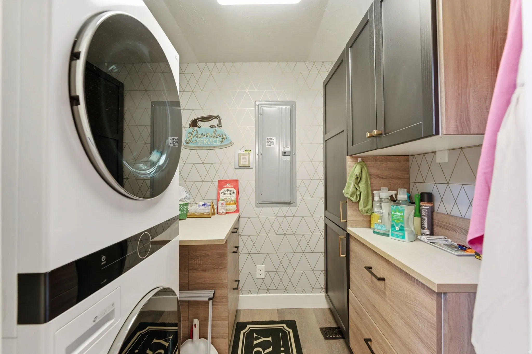 Laundry room with stacked washer / dryer, electric panel, and cabinet space