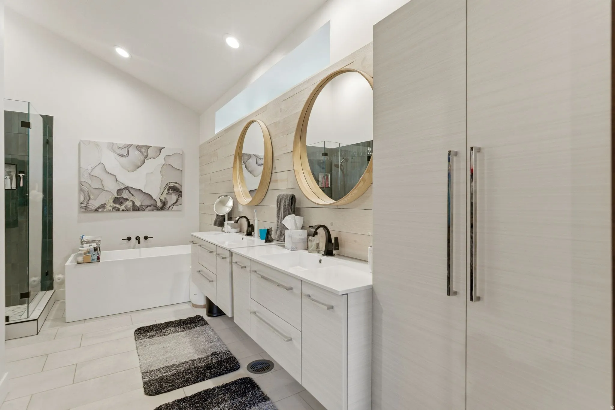 Bathroom with double vanity, a soaking tub, vaulted ceiling, a shower stall, and light tile patterned floors