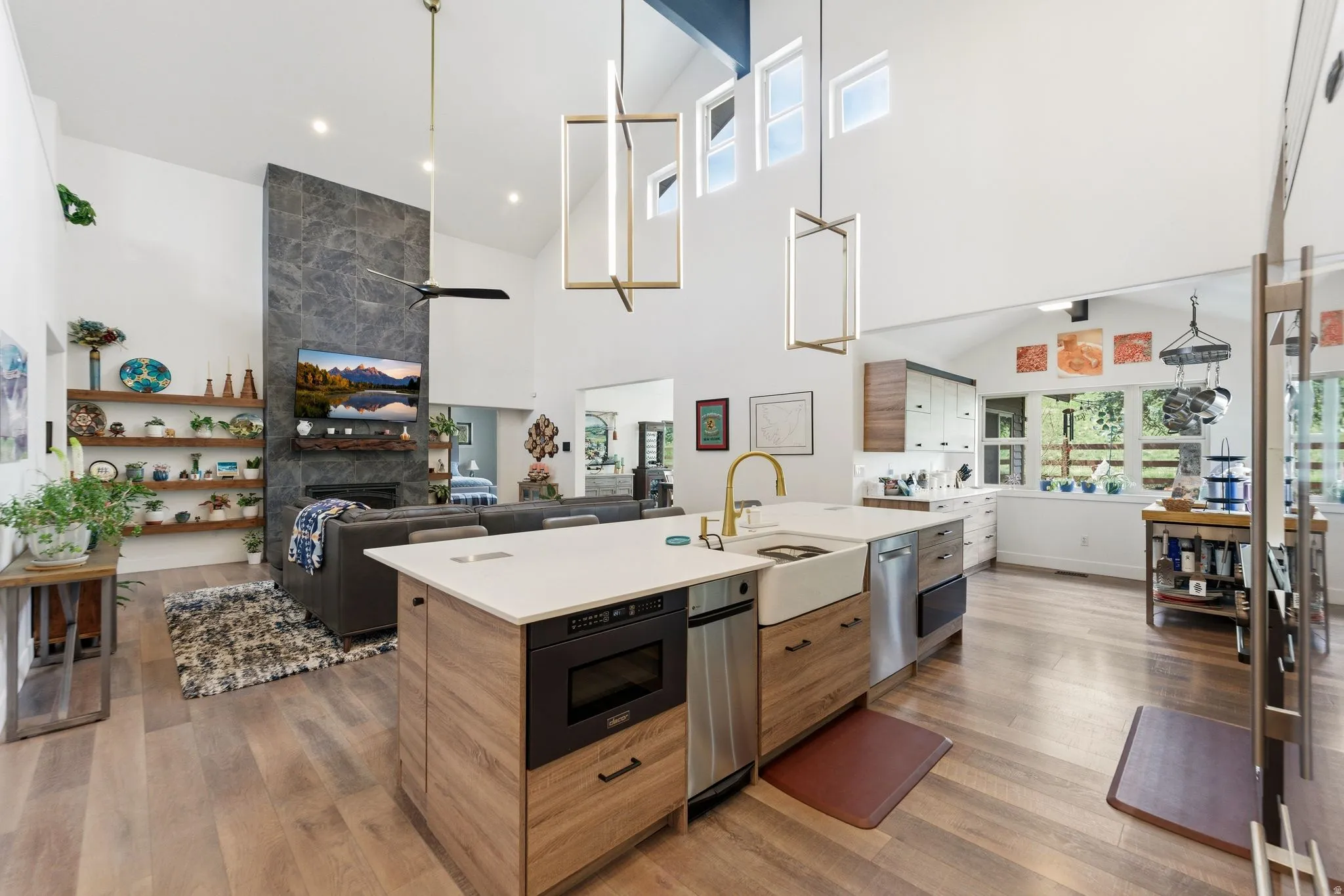 Dual tone kitchen with open floor plan, hanging light fixtures, a fireplace, lofted ceiling, and two tone cabinetry