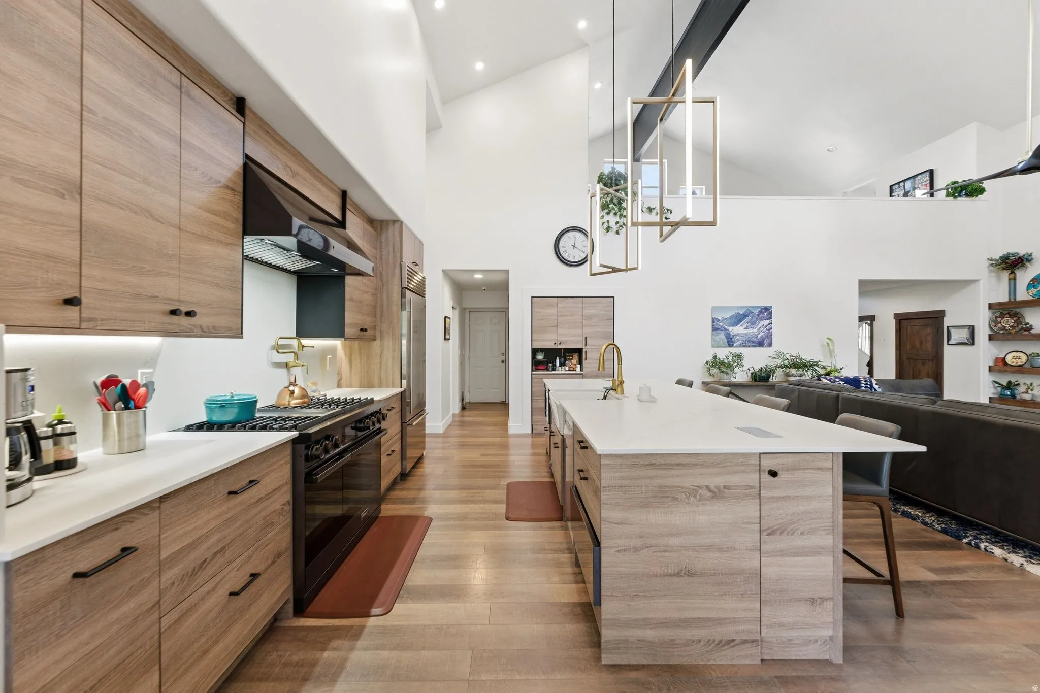 Kitchen with open floor plan, a kitchen breakfast bar, black gas range oven, modern cabinets, and decorative light fixtures